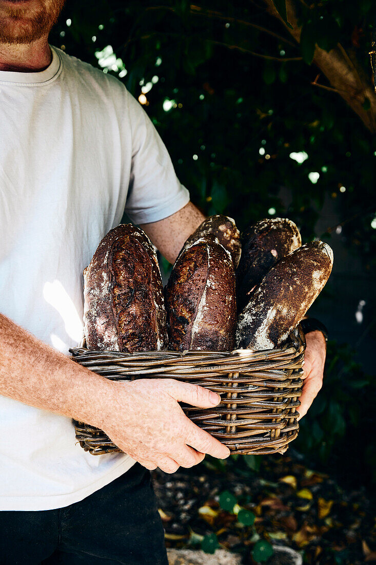 Mann hält Korb mit selbst gebackenen Broten