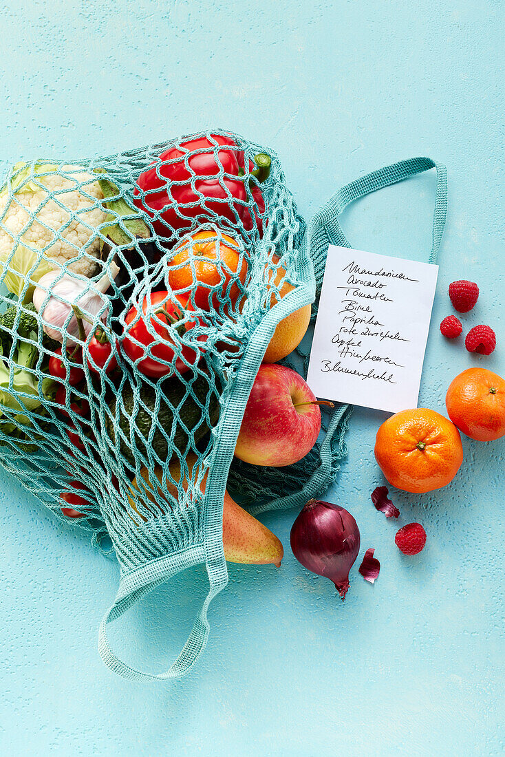 A net shopping bag with fruits, vegetables and a shopping list