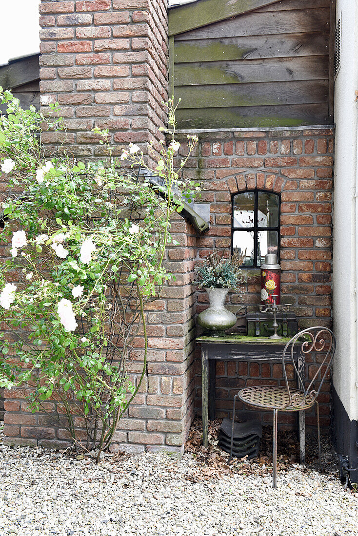 Small seating area on gravel terrace next to brick wall