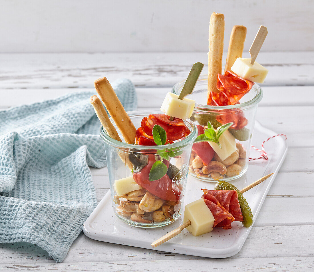 Salami and cheese skewers and bread sticks in jars
