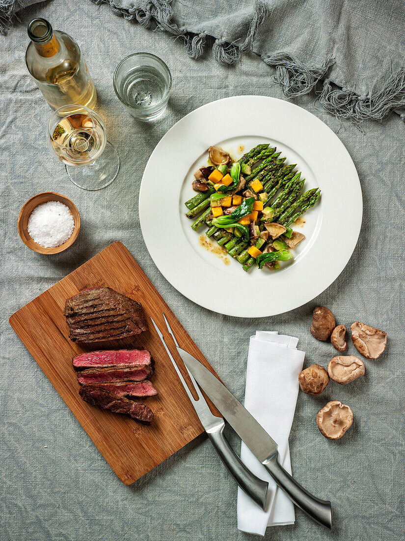 A grilled steak and green asparagus with mango and mushrooms