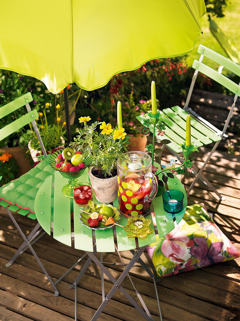 Bistrotisch mit Blume, Früchten und Kerzen auf der Terrasse