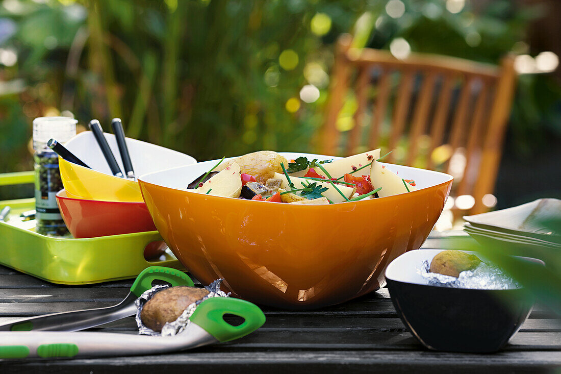 Bunte Schale mit Kartoffelsalat auf Gartentisch