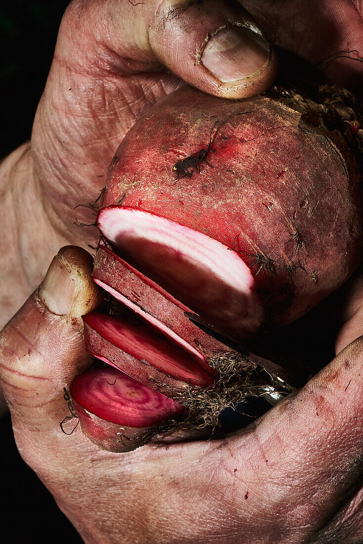 Hands holding a beet partially sliced