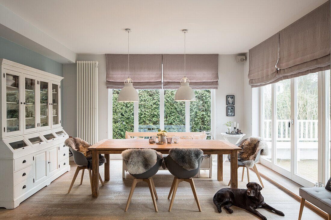 White dresser, table and shell chairs in dining room with door leading onto terrace