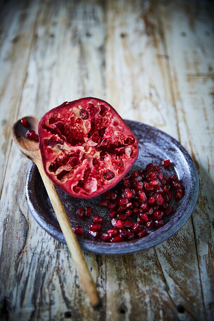 Half of a Pomegranate and pomegranate seeds on a plate