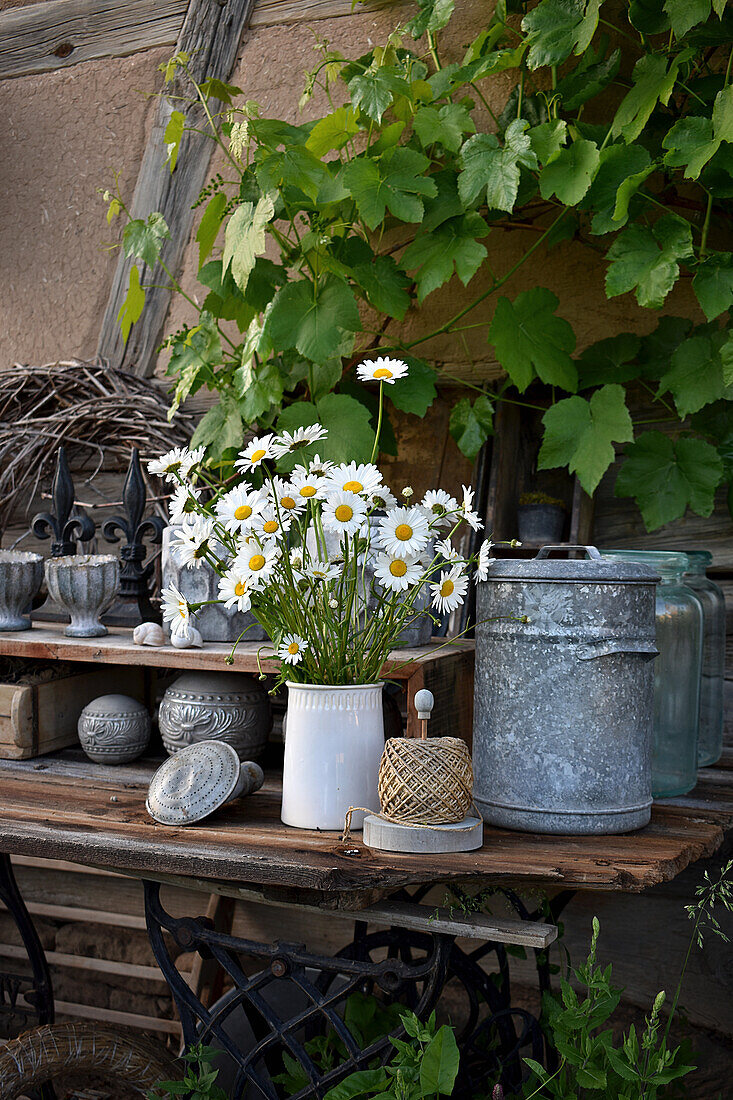 Bouquet of spring daisies on DIY work table made of old wooden door and sewing machine table