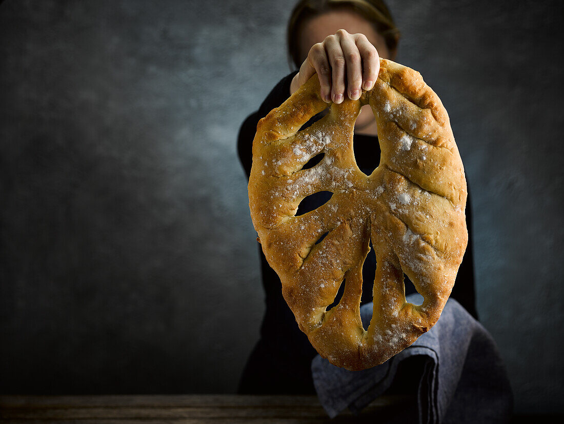 A hand holding a fougasse