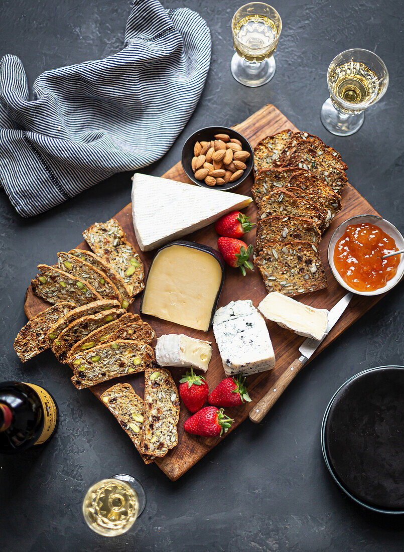 A cheese platter with bread, strawberries and almonds