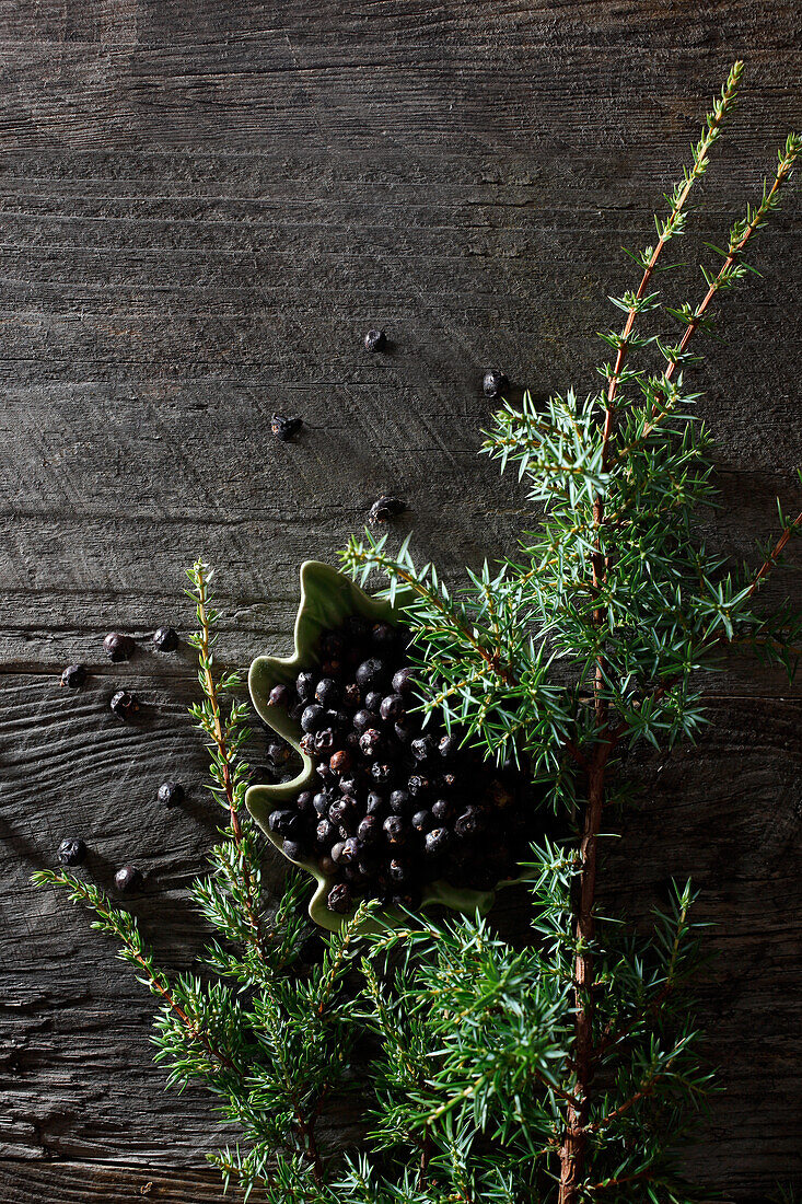 Juniper berries and juniper sprigs on a wooden surface