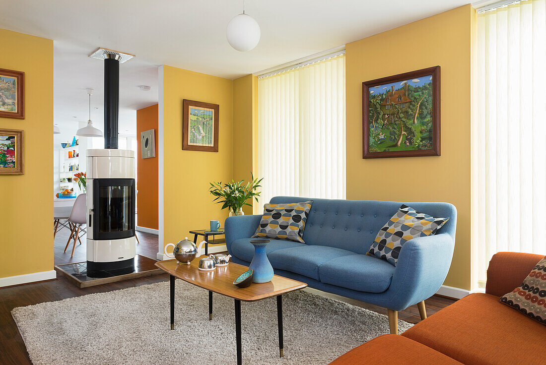 Blue upholstered sofa and coffee table in the seating area with yellow walls, passageway with fireplace