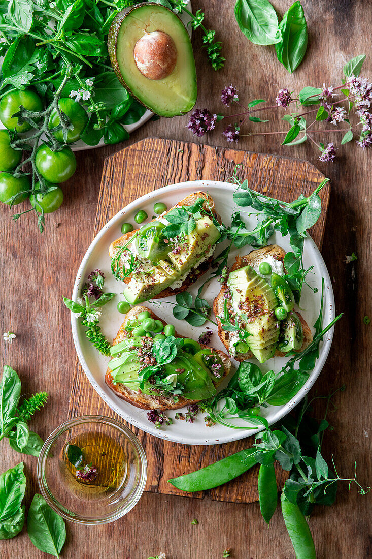 Bread slices topped with avocado, green tomatoes and peas