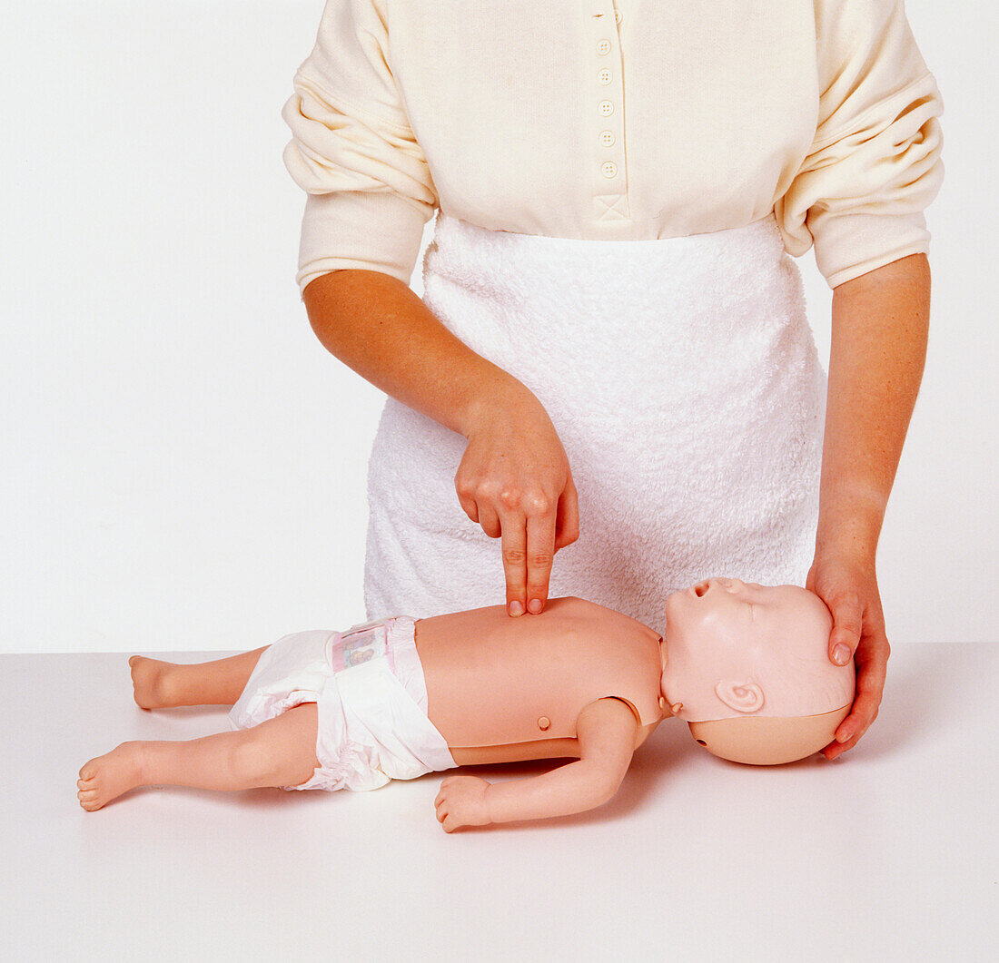 Woman pressing two fingers on chest of dummy