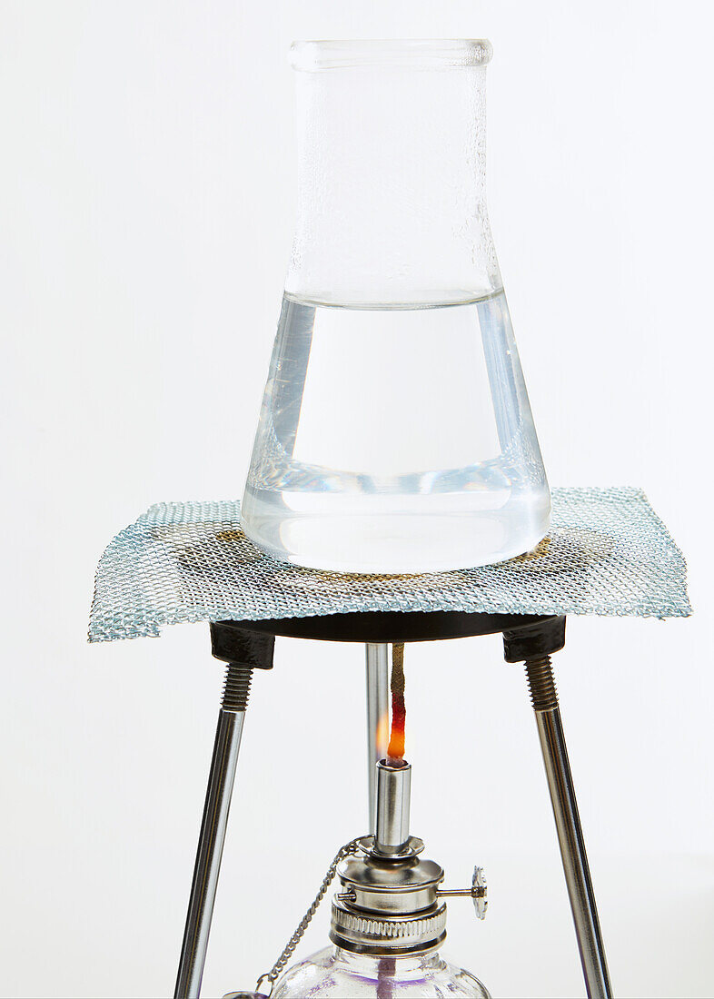 Conical flask on a tripod containing water being heated