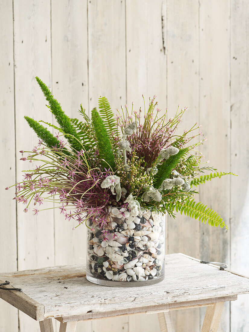 Flowers in vase filled with seashells