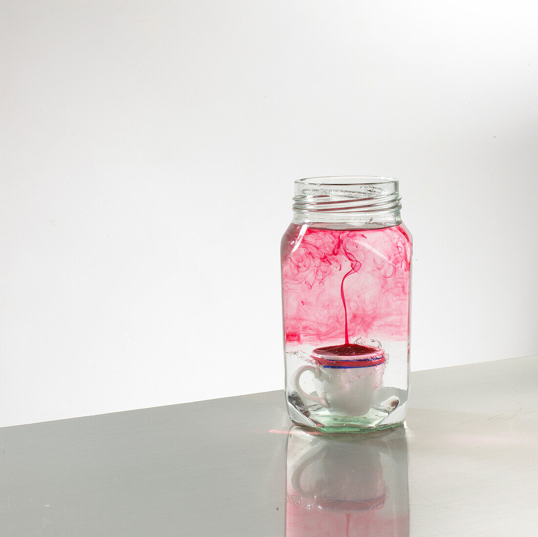 Coffee cup inside glass jar containing cold water