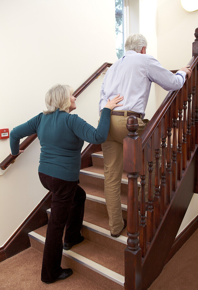 Woman supporting man as he climbs stairs