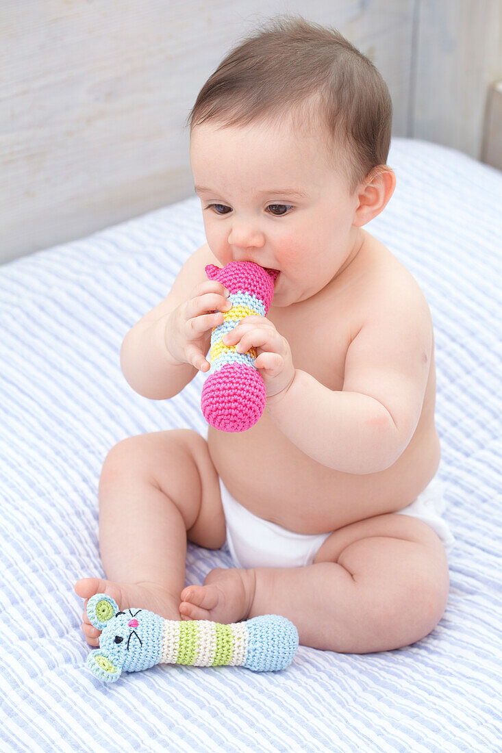 Baby girl holding crocheted animal rattles