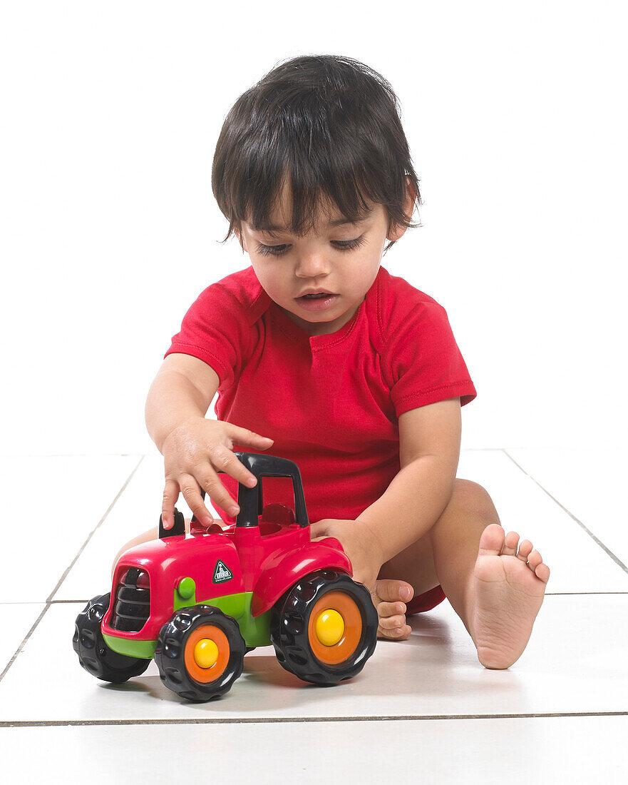 Baby boy sitting with toy tractor