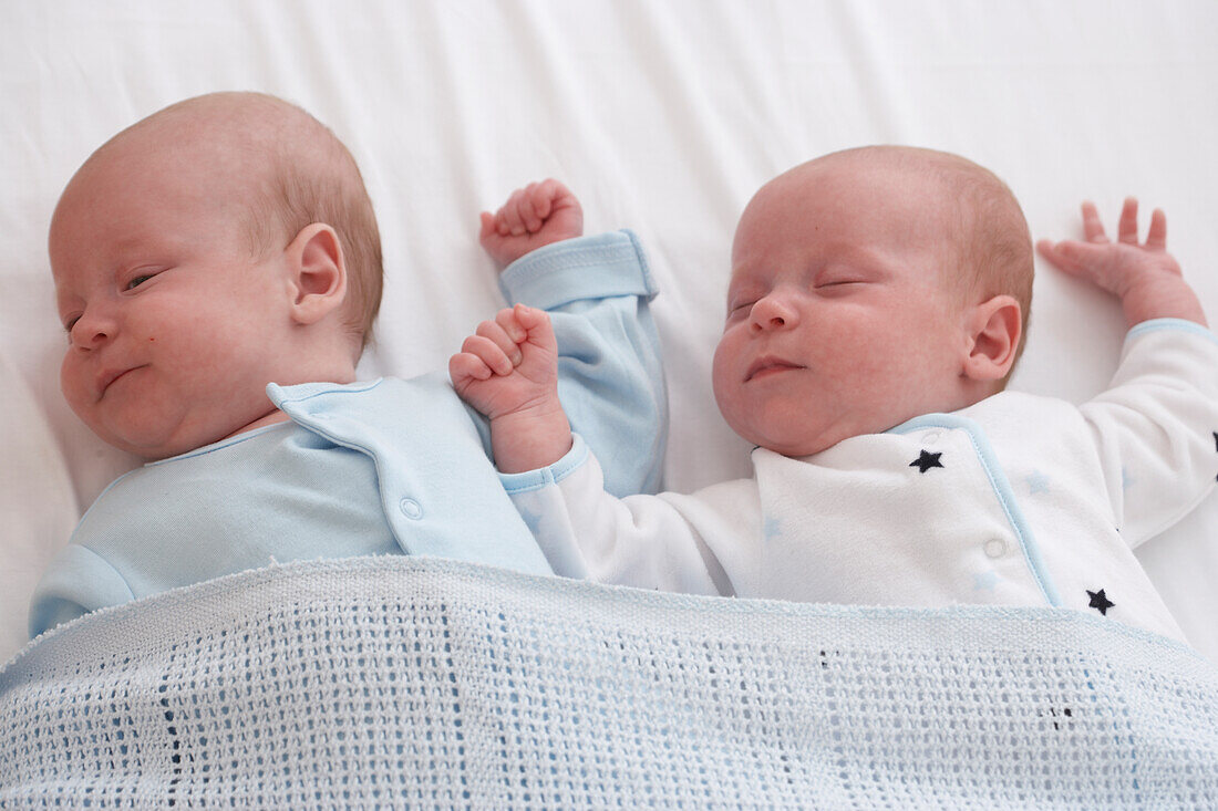 Twin baby boy and girl asleep in cot together