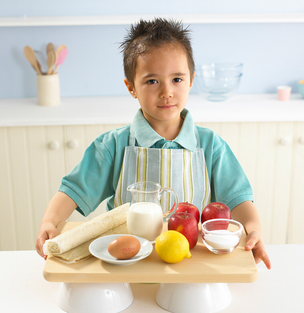 Boy holding the ingredients for apple meringue tarts