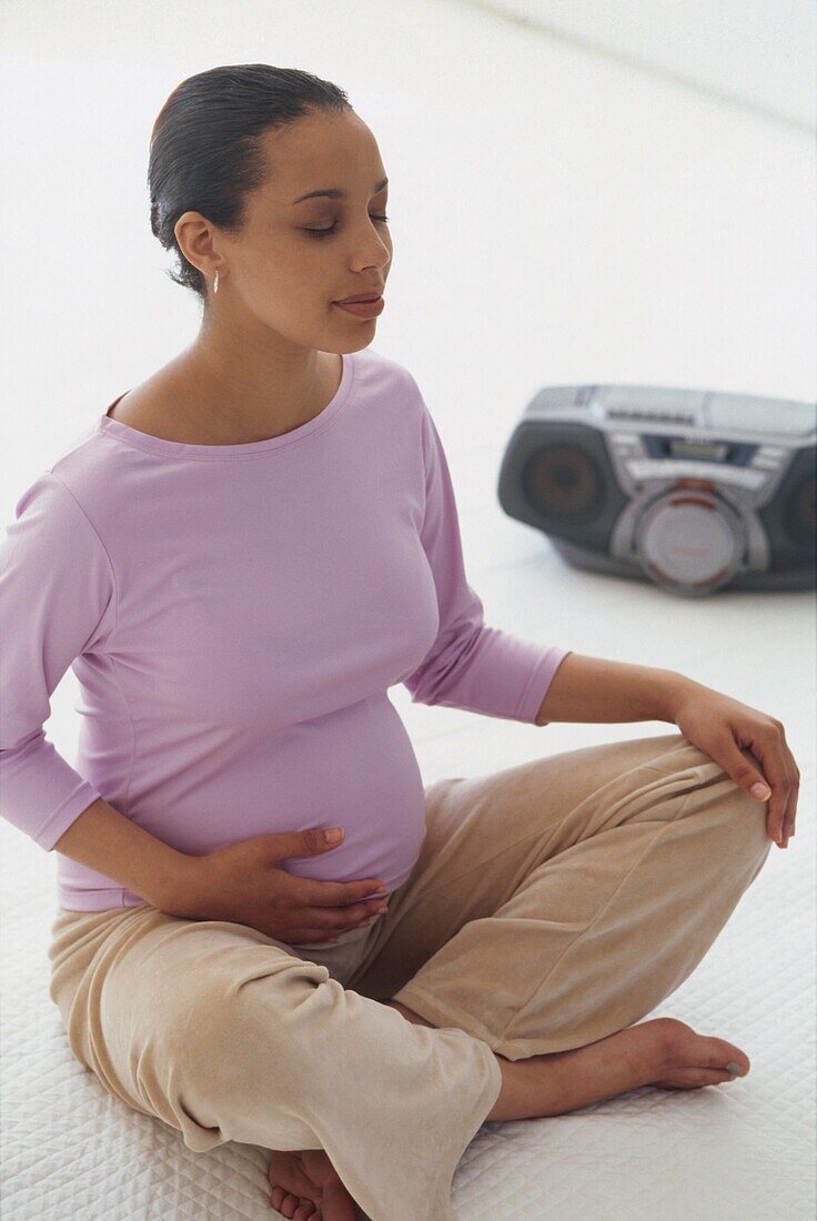 Pregnant woman sat on floor meditating