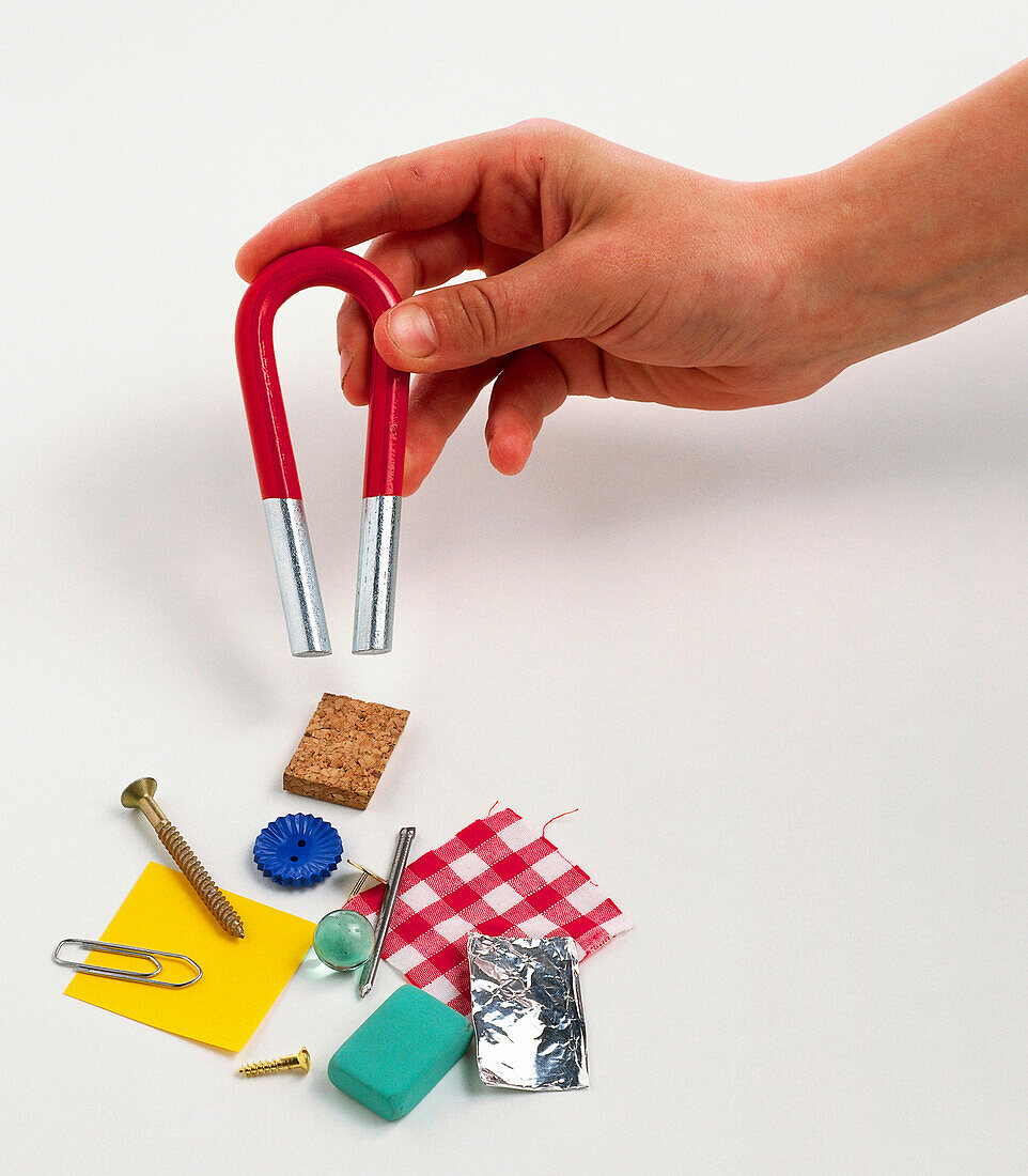 Child's hand lowering magnet over household objects