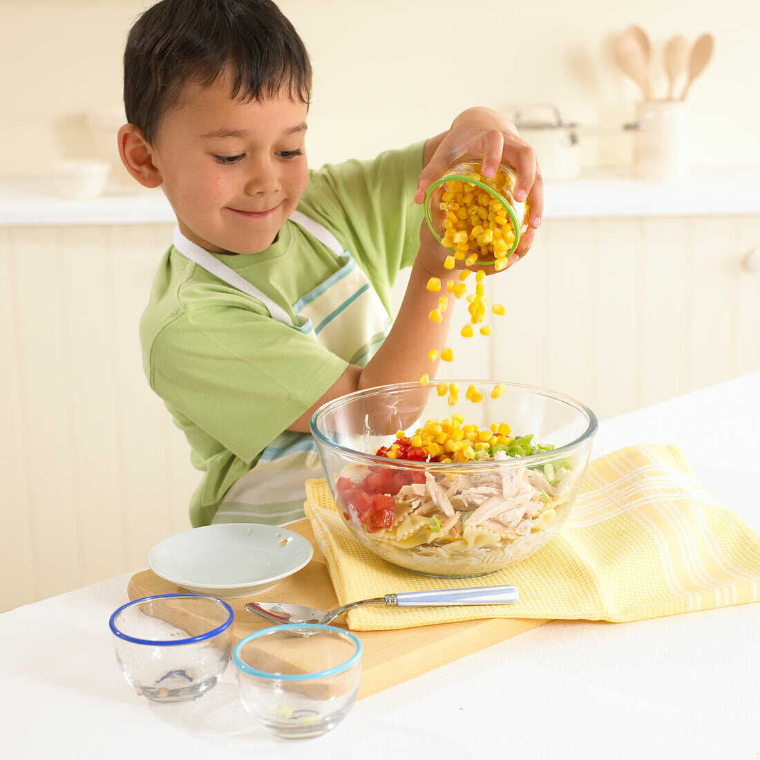 Boy tipping sweetcorn into a bowl for pasta salad