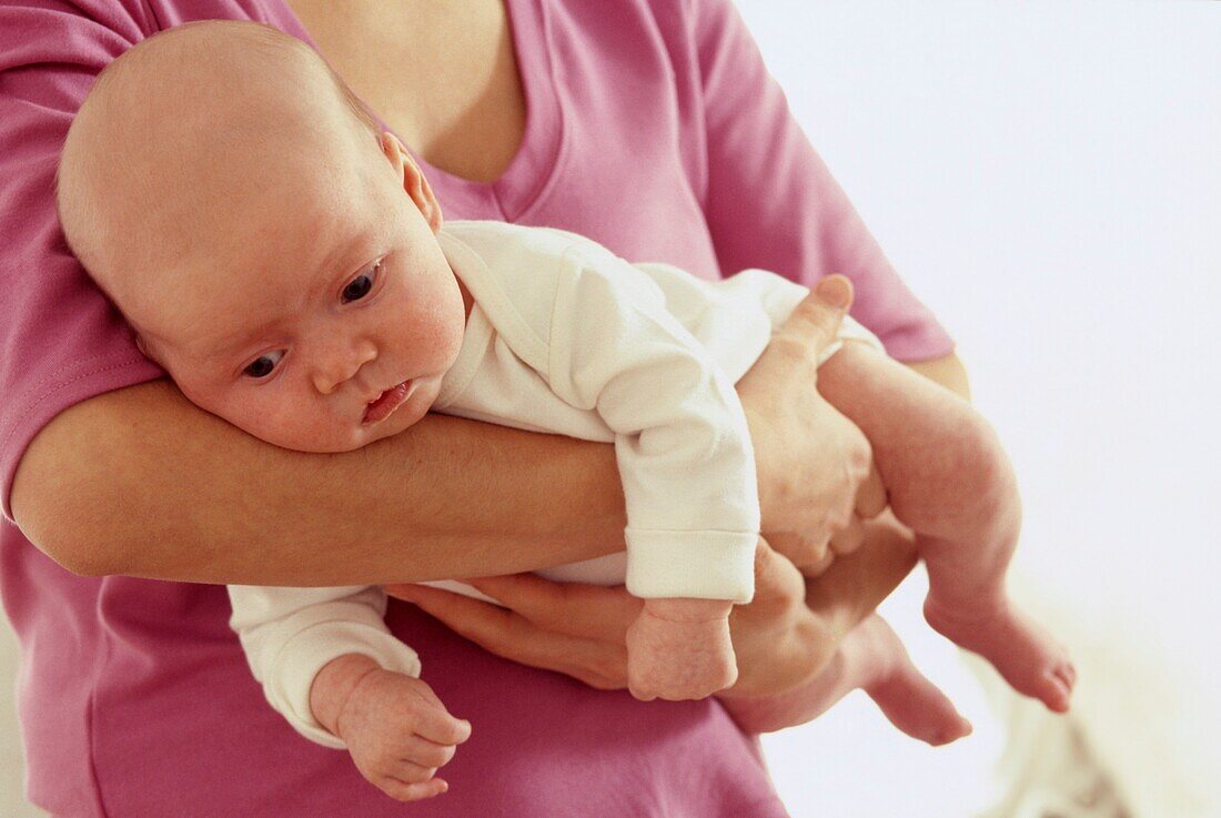 Woman holding young baby girl across her forearms