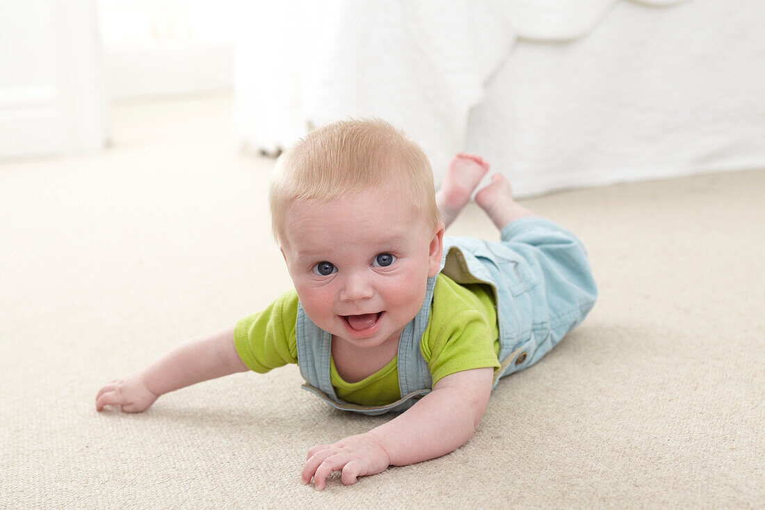 Smiling baby boy crawling on carpet