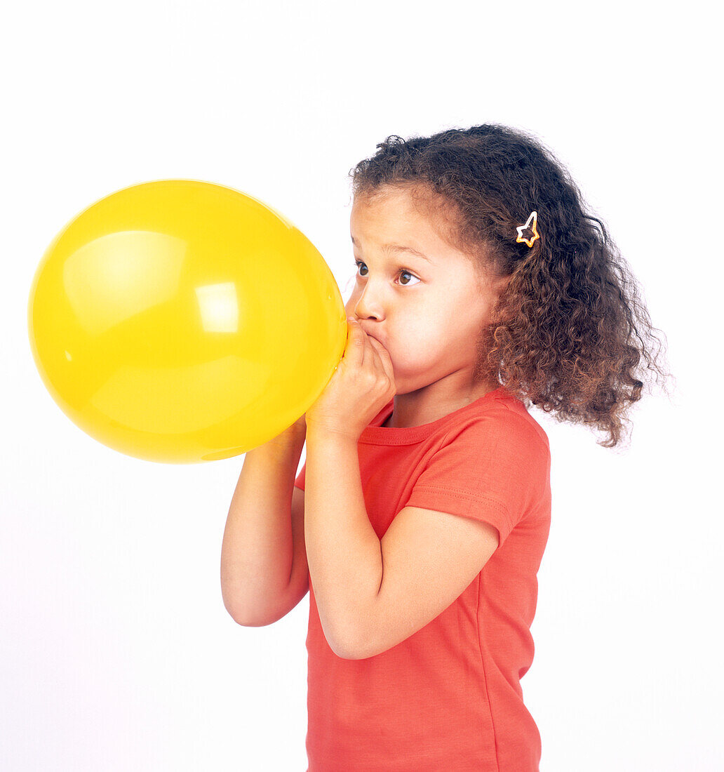 Girl inflating yellow balloon