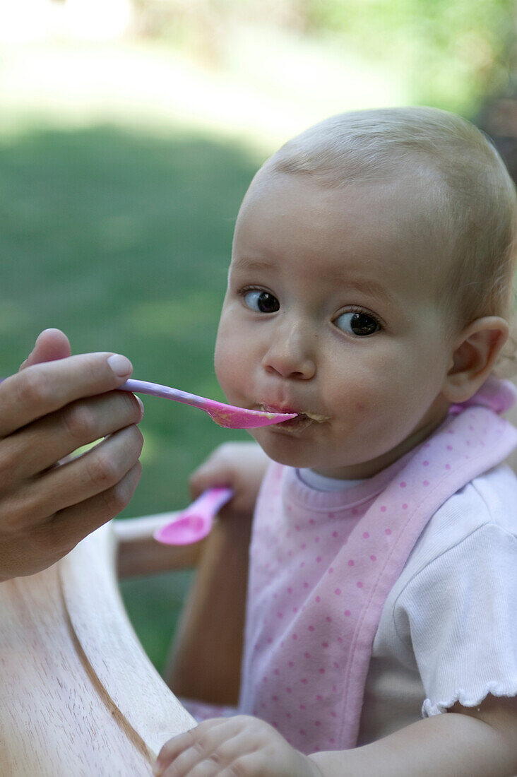 Baby girl being spoon fed baby food