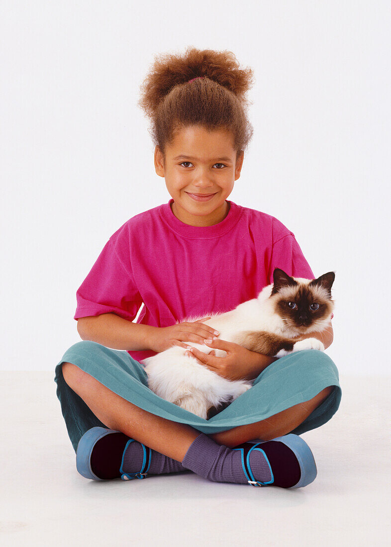 Smiling girl holding Birman cat on her lap