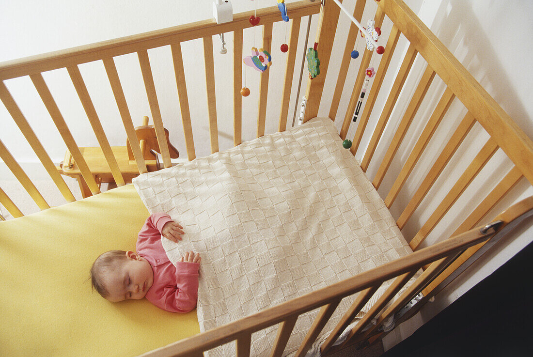 Baby girl sleeping in wooden crib