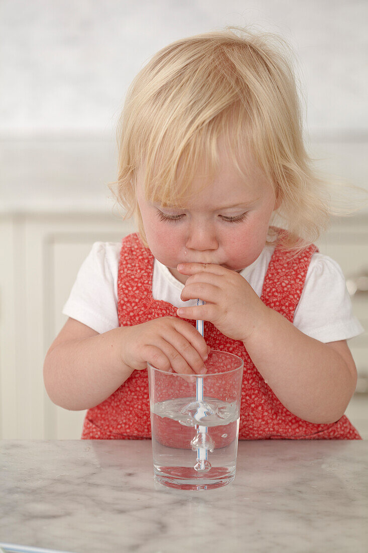Girl drinking water from glass with a straw