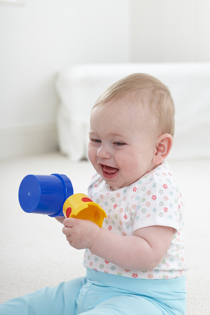 Smiling baby girl playing with plastic cups