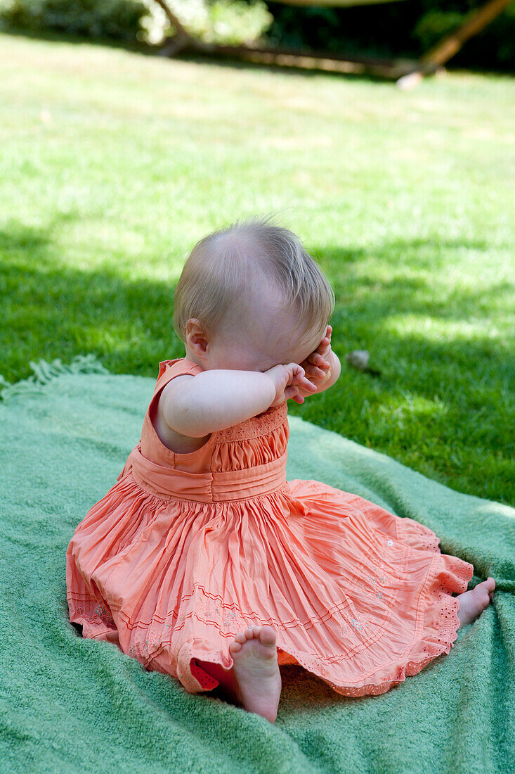 Baby girl sitting on rug outdoors