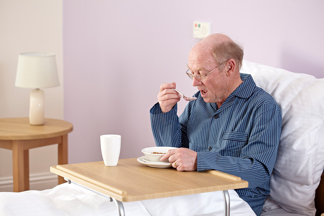 Man sitting up in bed eating using portable table