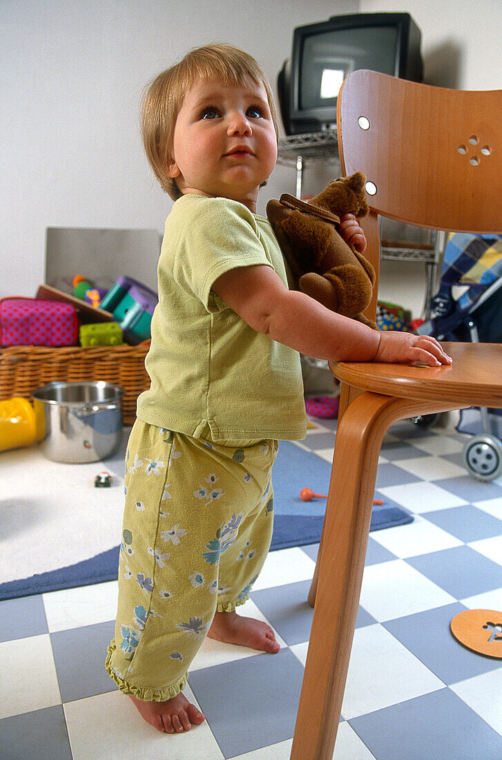 Toddler standing with a toy in one hand