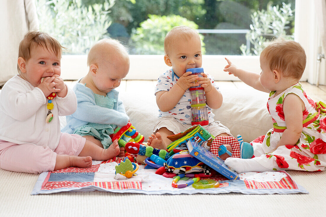 Three baby girls and baby boy playing with toys indoors
