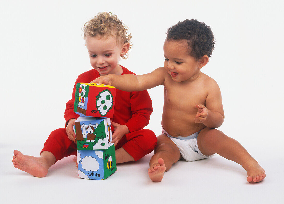 Two children stacking soft cube toys