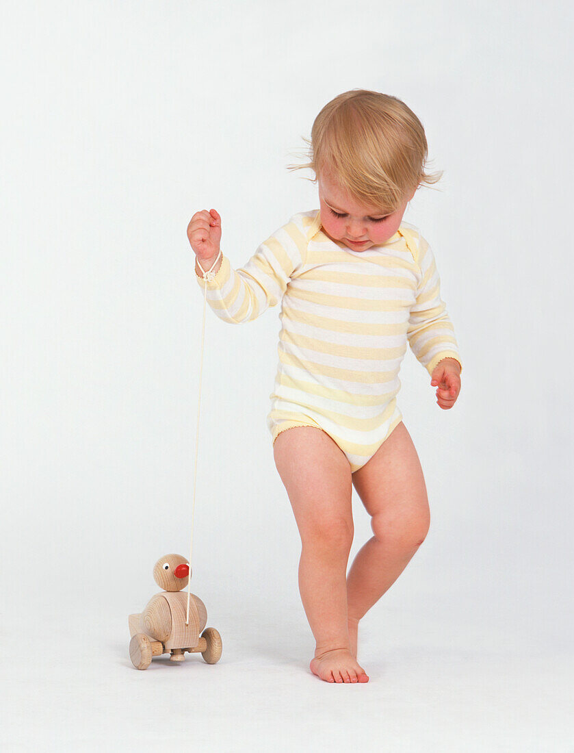 Baby girl with wooden duck toy on a string