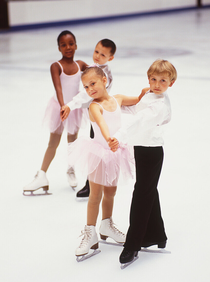 Two young ice skating couples about to perform