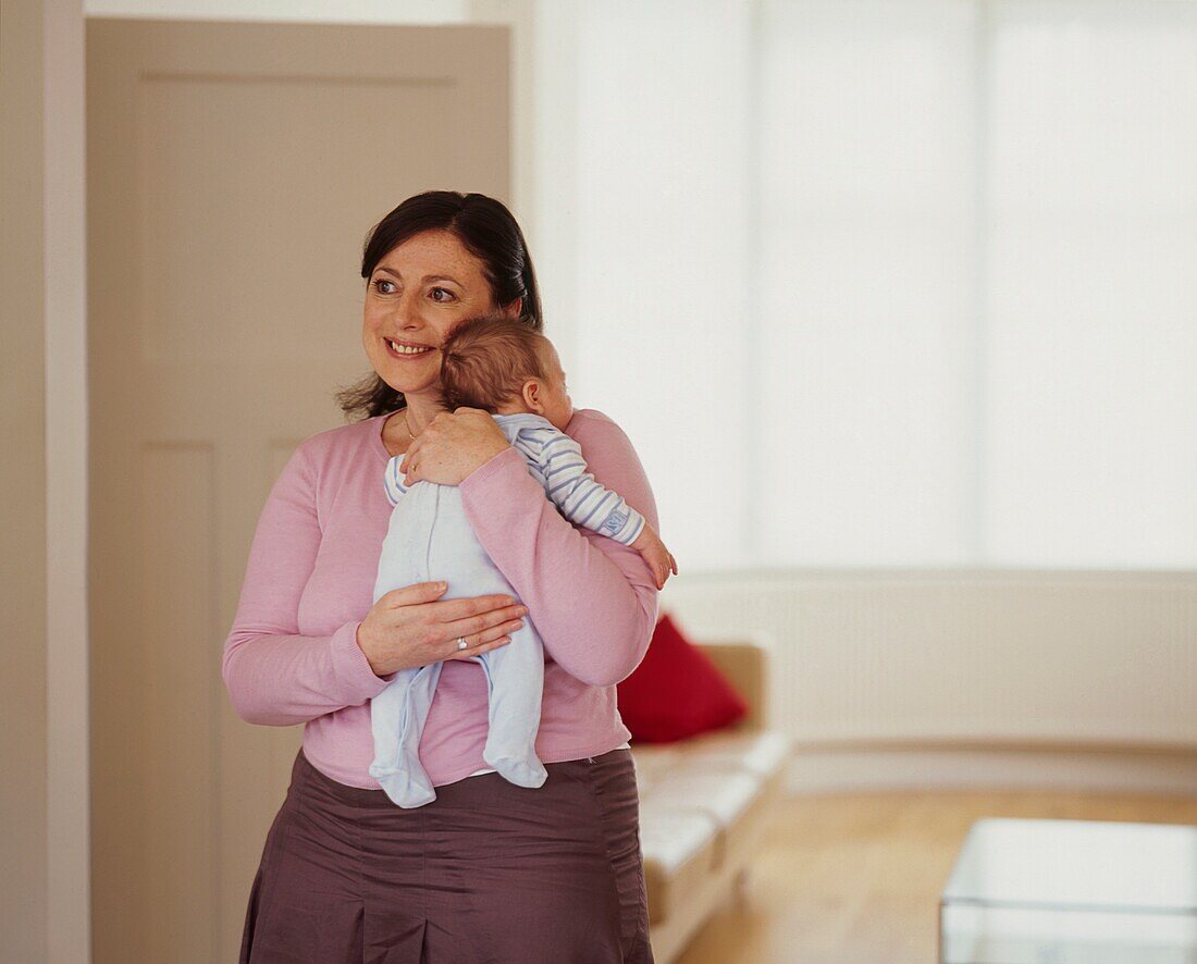 Woman holding baby boy securely in her arms and smiling