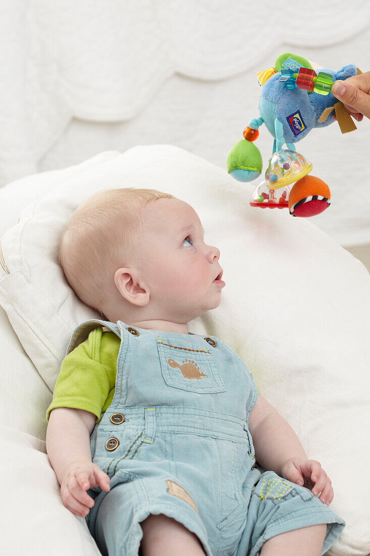 Person holding activity toy above head of baby boy