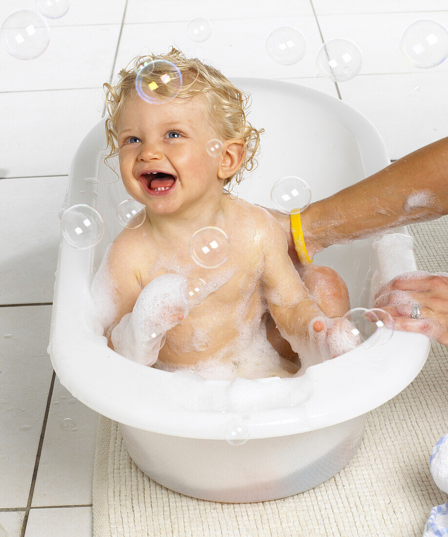 Boy in bath tub catching bubbles