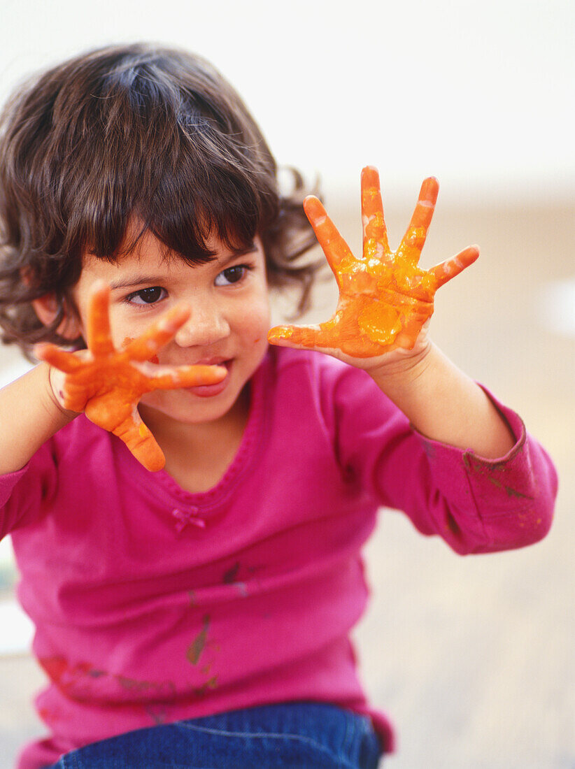 Girl holding up hands covered in paint