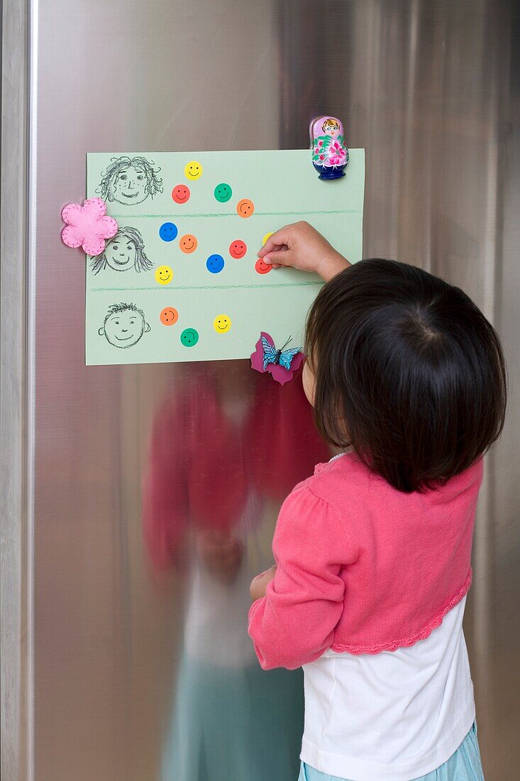 Girl putting smiley-face stickers on chart