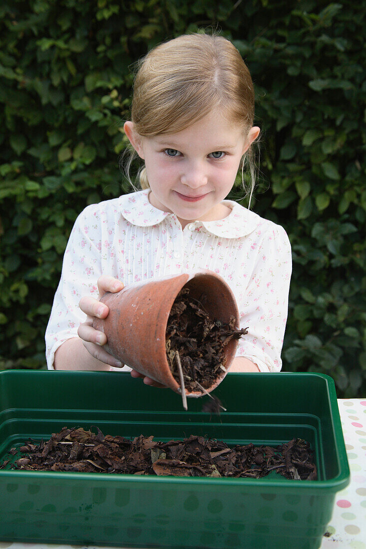 Girl holding plant pot filled with compost