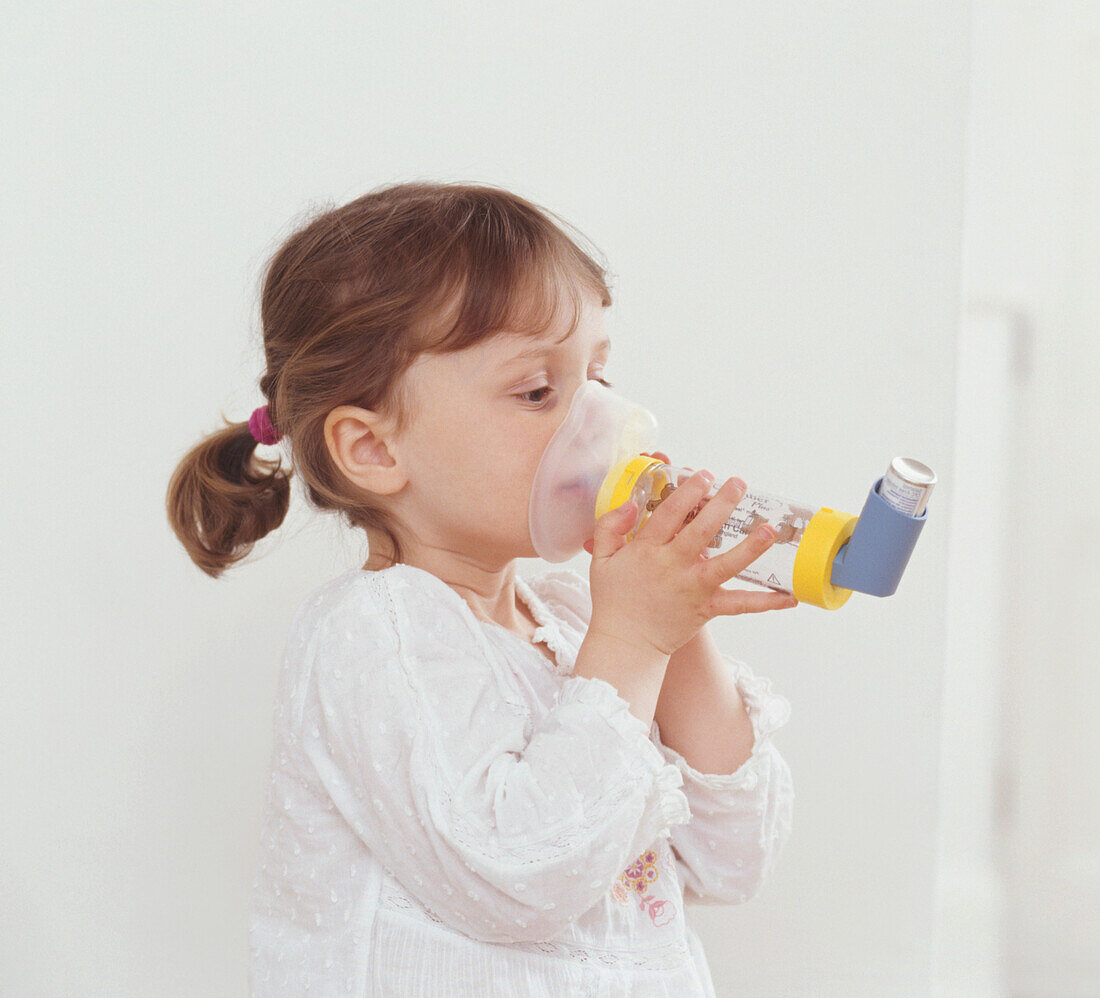 Girl using spacer device with asthma inhaler
